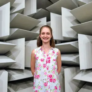 Lucy Richardson, female noise and acoustics engineer, smiles at camera in anechoic chamber