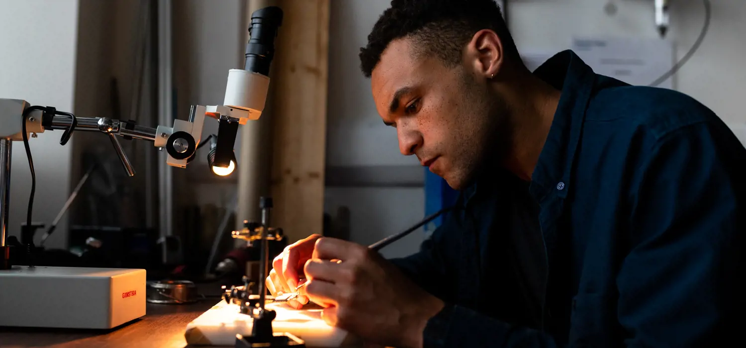 Male mechanical engineer solders a circuit board