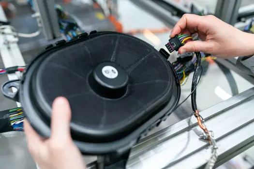 Female electronics and quality engineer plugs in speaker in workshop