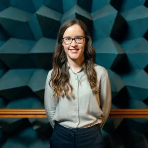 Orla Murphy, female engineering quality manager, smiles at the camera in an anechoic chamber