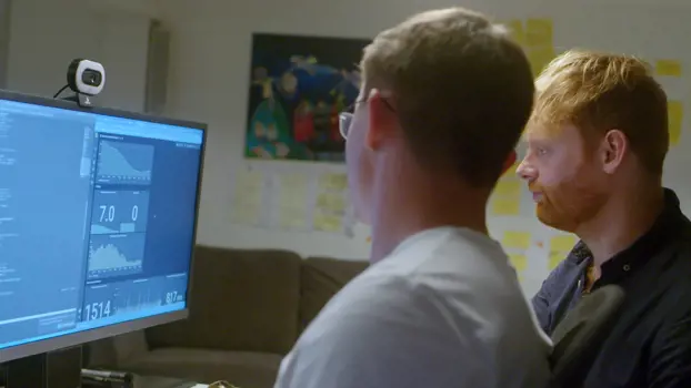 Two male software engineers looking at code on a desktop screen