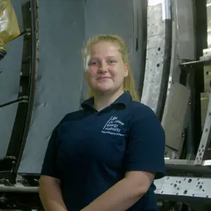 Charlotte Wilkes, female apprentice mechanical engineer smiling in workshop environment