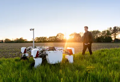  Male mechanical engineer with sustainable agricultural robot in field 