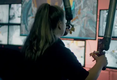 Female apprentice mechanical engineer uses robot